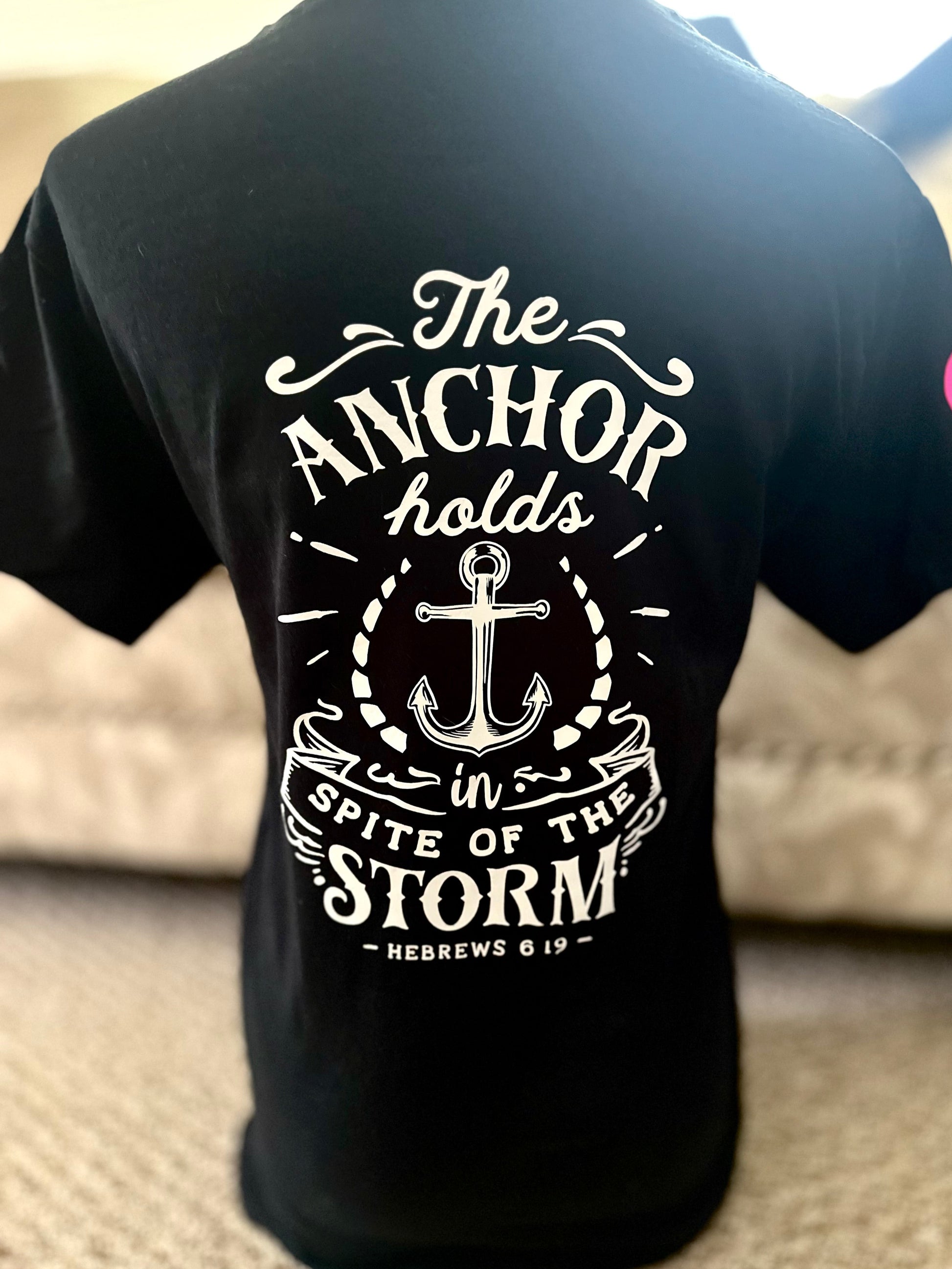 Black t-shirt with white anchor design and text on the back, worn by a person.